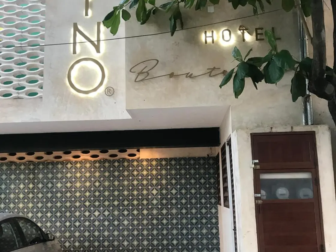 Acceso de noche con el letrero iluminado sobre muro de concreto y celosía