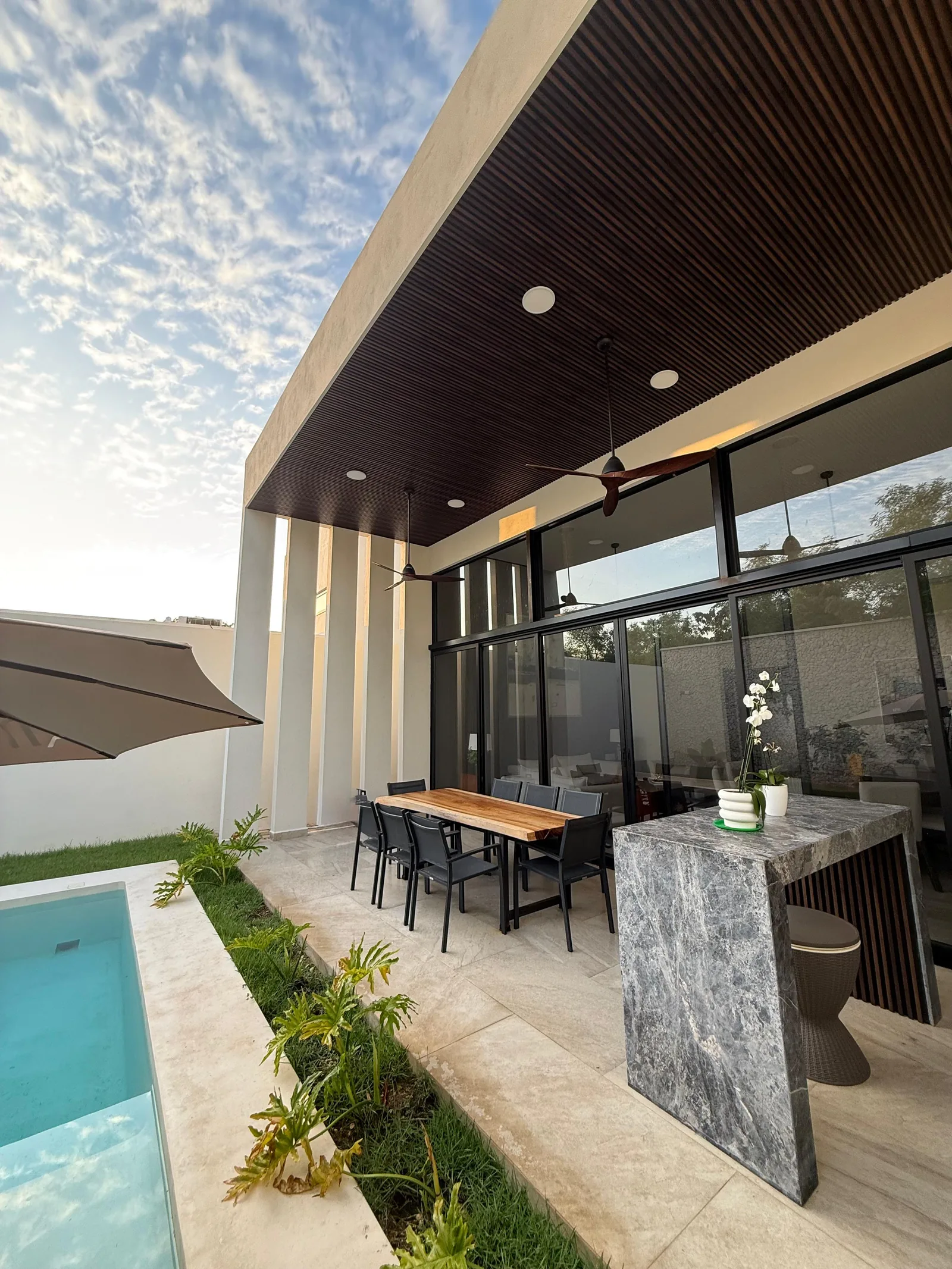 Terraza techada con plafón de duela y barra de mármol